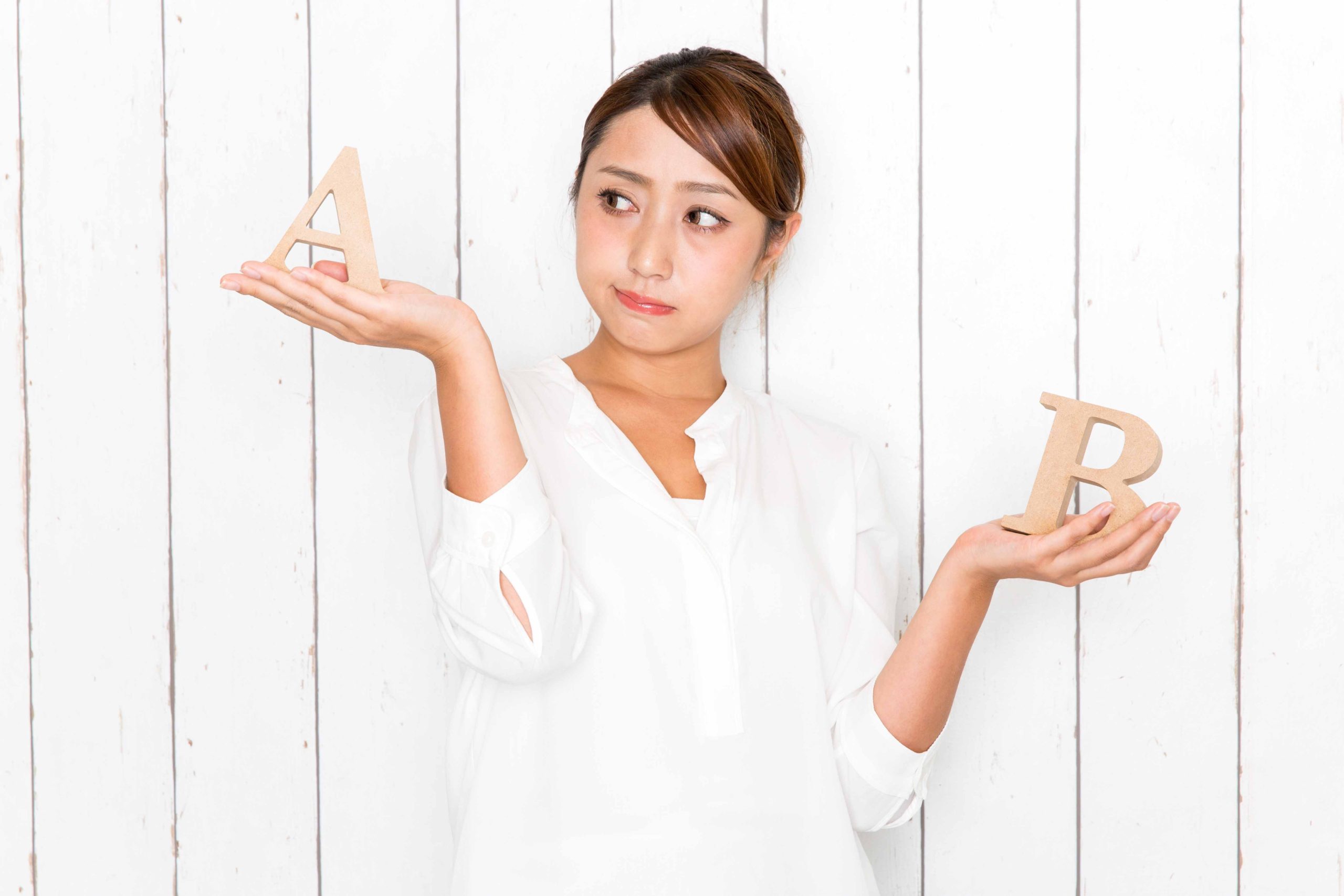 白いシャツを着た女性がどちらがいいか悩んでいる