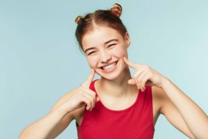 両頬に指を当てている笑顔の女性