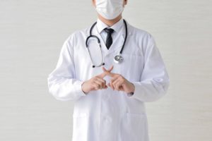 両手の人差し指でバツを示している医者
