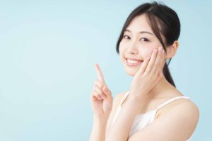 キャミソールを着た女性が左手を頬に当て、右手の人差し指を立てている