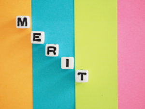 カラフルな背景にMERITと書かれたブロックが置かれている