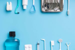 水色の背景の前に歯の治療器具やマウスウォッシュ、歯ブラシ、歯磨き粉などが置かれている
