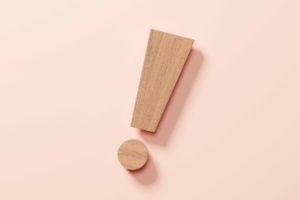 薄オレンジの背景の前に木製のびっくりマークが置かれている