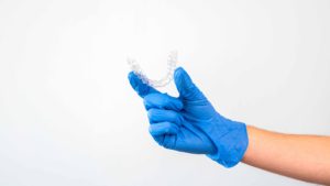 青いゴム手袋を着用した手でマウスピースを持っている