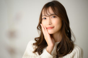 頬を手のひらで押さえて微笑んでいる長髪の女性