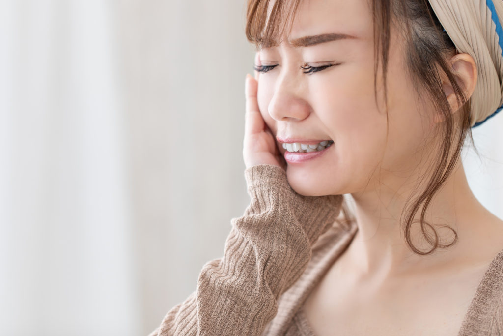 右頬に手を当てて痛がる女性
