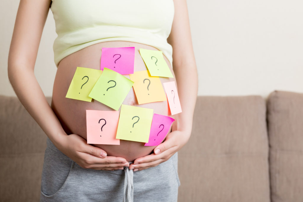 妊娠して膨らんだお腹に？が書かれたメモを貼る