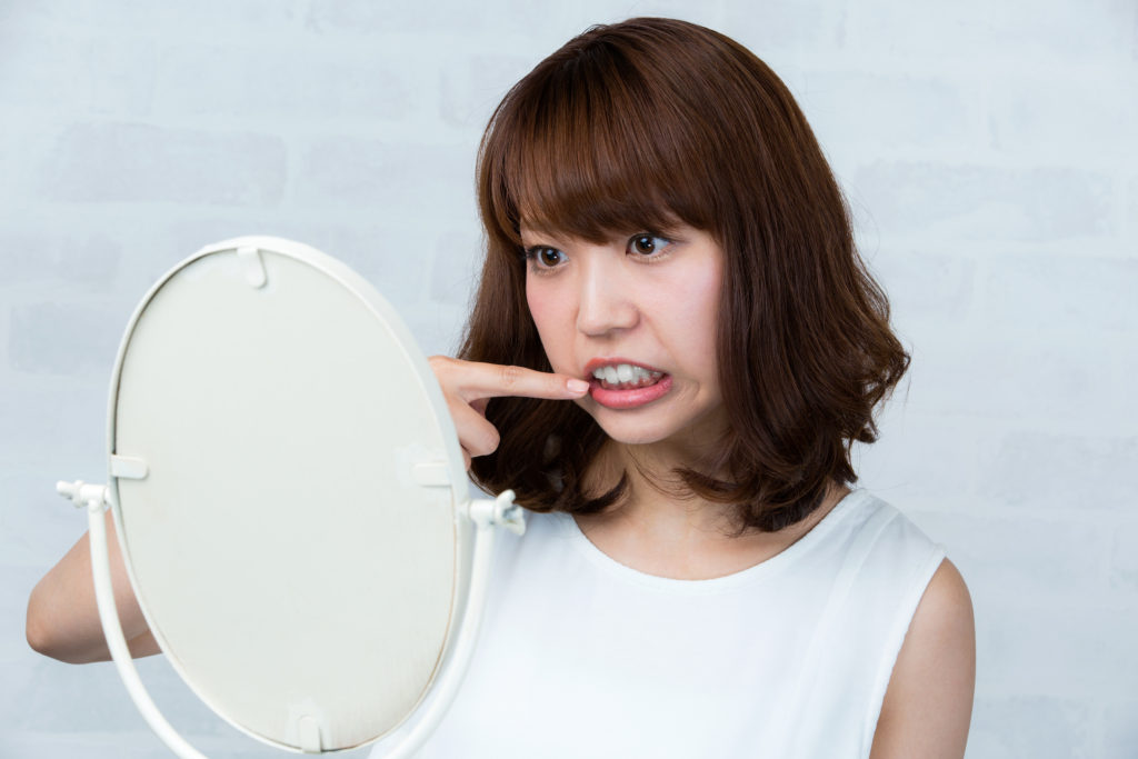 鏡を見て自分の歯並びを確認する女性